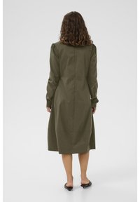Robe midi vert olive à manches longues, dotée d'une coupe droite et de légères fronces aux épaules. Fabriquée en tissu lisse et léger.