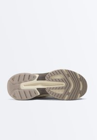 Podošva béžovo-hnedej tenisky s textúrovaným dezénom a vyrazeným názvom značky "Oysho" v strede.