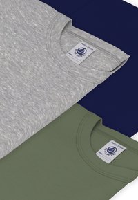 Τρία βαμβακερά μπλουζάκια στοιβαγμένα: γκρι, ναυτικό μπλε και ελαι πράσινο. Στρογγυλές λαιμοκοπές, ορατές λεπτομέρειες ραφής και ετικέτες με πληροφορίες για το εμπορικό σήμα.