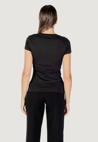 T-shirt nera aderente con maniche corte e scollatura rotonda, realizzata in tessuto liscio, che mostra una texture sottile e una silhouette pulita.