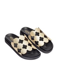 Chanclas negras con una correa dorada texturizada que presenta formas de estrellas recortadas. Plantilla suave y un diseño minimalista.