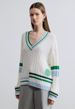 Weißer Strickpullover mit V-Ausschnitt, mit grün-blauen Streifenmustern, strukturierter Zopfmuster-Strick und einem runden Logo auf der Vorderseite unten.