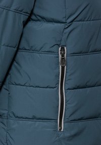 Giacca puffer di colore blu navy con design trapuntato, dotata di una cerniera nera con accento grigio. Tessuto liscio, leggero e isolante.