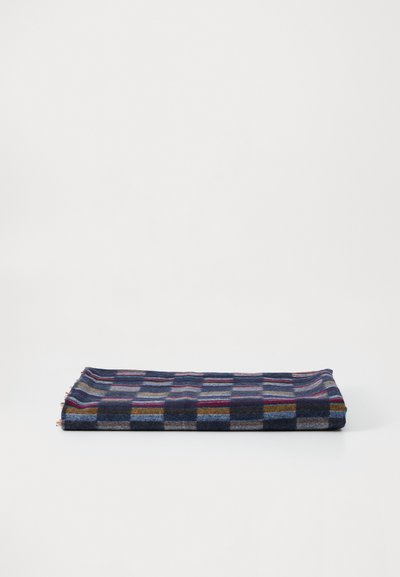 Plaid vilnos antklodė, turinti tamsiai mėlyną pagrindą su daugiaspalvėmis langeliais. Kraštai nupjauti, kad suteiktų tekstūros. Sulankstyta plokščiai.