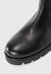 Schwarze Lederstiefelette mit runder Zehenform, glatter Textur und einer dicken, robusten Sohle mit Profil für guten Halt.