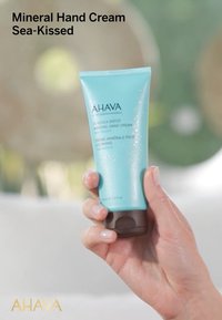 Tubetto turchese di crema per mani con base marrone, caratterizzato da una finitura testurizzata e un'etichetta con testo bianco che indica crema per mani minerale.