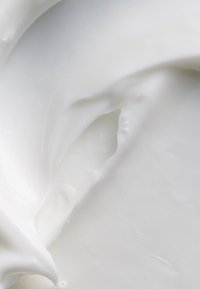 Sostanza bianca densa e cremosa con una texture liscia e lucida, caratterizzata da una leggera spirale e un'incavatura, che ricorda la panna montata o la crema idratante.