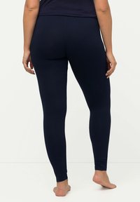 Leggings blu navy realizzati in un tessuto morbido ed elasticizzato, adattati lungo le gambe con una texture liscia e un design alla caviglia.