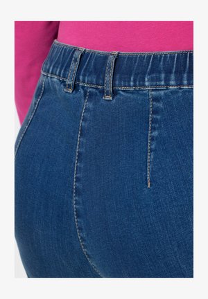 Tummansiniset farkut, joissa on korkea vyötärö ja sileä pinta, näkyvät saumat sekä suora malli.