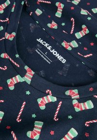 Camisa de algodón azul marino con un patrón festivo de medias verdes, bastones de caramelo rojos y blancos, y estrellas rojas. La etiqueta dice "JACK & JONES."