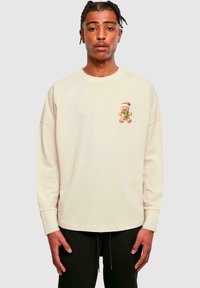 Cremefarvet sweatshirt med lange ærmer, der har et peberkagemand grafik med en rød hat på brystet. Blødt stof og afslappet pasform.