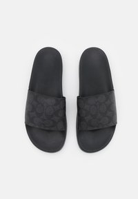 Sandalias deslizantes negras con una correa texturizada que presenta un patrón circular oscuro y una plantilla mate suave. Diseñadas para uso casual.