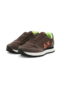 Une paire de baskets en suède et en tissu marron avec un logo orange, une semelle noire et blanche, et un intérieur en néon vert.