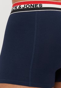 Boxer shorts bleu marine au design ajusté. Dotés d'une large ceinture élastique avec un logo en noir, rouge et blanc. Texture lisse et douce.