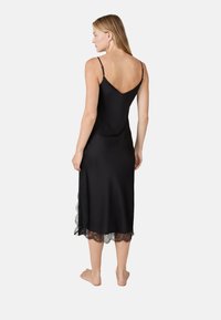 Robe nuisette en satin noir avec des bretelles spaghetti réglables, un décolleté en V et une délicate bordure en dentelle à l'ourlet. Texture lisse, design long jusqu'aux chevilles.