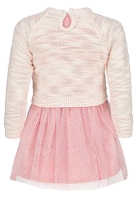 Rosa stickad tröja med rund halsringning och ett nyckelhål bak, i kombination med en rosa, semi-transparent glittrig tyllkjol med veck.