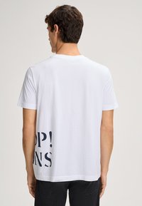 Weißes Baumwoll-T-Shirt mit kurzen Ärmeln und Rundhalsausschnitt, mit einem großen dunkelblauen Textgrafik auf der linken Seite des Rückens.