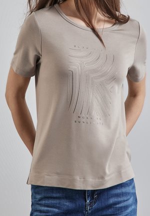 Hellbeige T-Shirt mit kurzen Ärmeln und Rundhalsausschnitt, mit einem erhabenen Grafikdesign und dem Text "SLOW YELLS MORNING SUNLIGHTS." Angenehm glatte Textur.