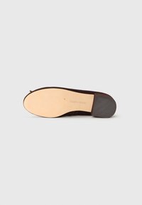 Sole of a brown flat shoe with a textured heel and smooth beige bottom, showing the "Steve Madden" brand name.