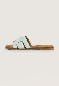 Lichtblauwe slidesandalen met een gestructureerde bovenkant en gekruiste banden. De binnenzool is van bruin suede, met een platte rubberen buitenzool.