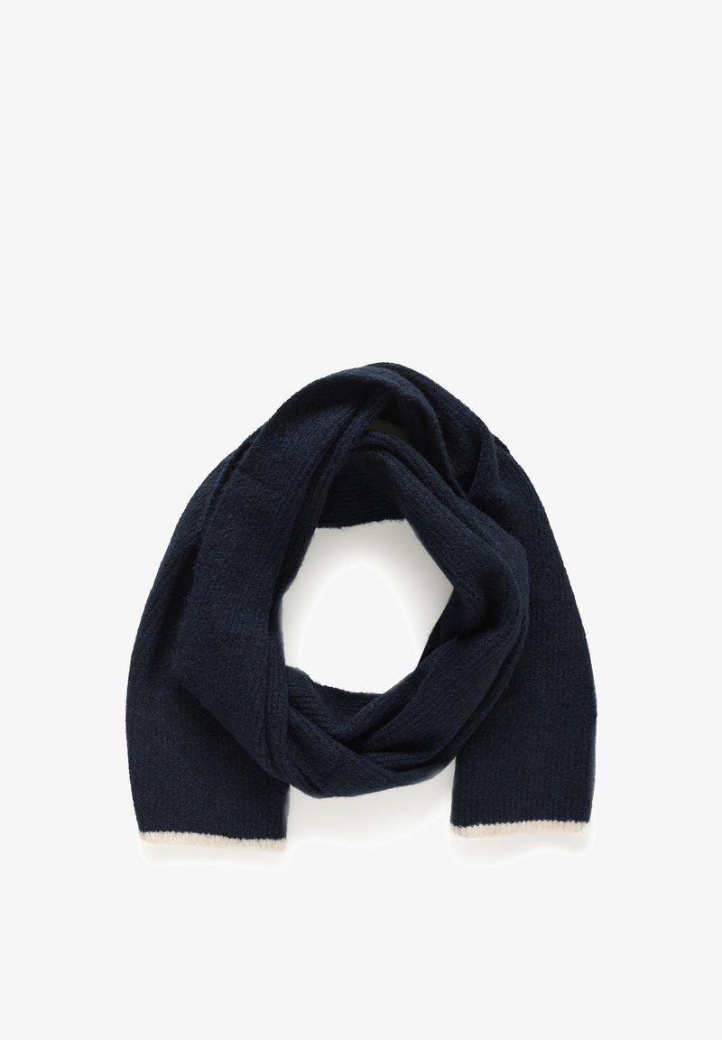 Navy pletený šátek s texturovaným povrchem a krémovými lemy na okrajích, vytvářející volný, kruhový tvar.