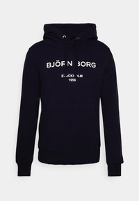 Felpa blu navy in cotone con tasca frontale a marsupio e cappuccio con coulisse. Presenta testo bianco: "BJÖRN BORG STOCKHOLM 1956."