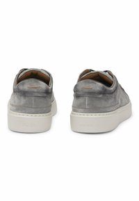 Sneaker in suede grigio con una finitura liscia, suola spessa bianca e dettagli di cucitura. Il tallone presenta un branding sottile sul retro.