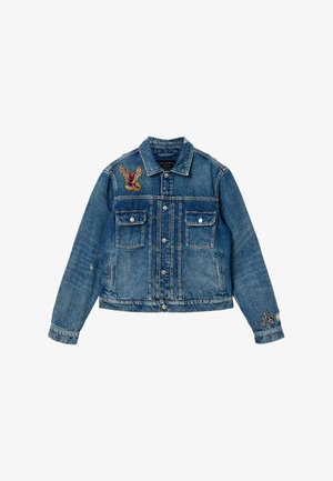 Blauwe spijkerjasje met knoopsluiting aan de voorkant, twee borstflapzakken, adelaar-applicatie op de linkerschouder en "AS" borduursel op de rechtermanchet.