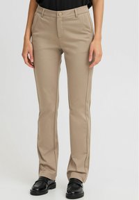 Pantaloni beige su misura realizzati in tessuto testurizzato, caratterizzati da un design a gamba dritta, tasche laterali e chiusura frontale con bottone.