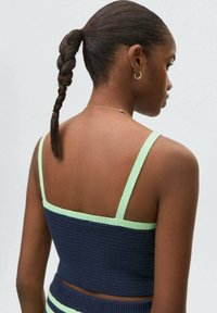 Námornícky pletený cropped top s mätovo zeleným remienkom a detaily lemovania. Vyznačuje sa texturovanou látkou a priliehavým strihom.