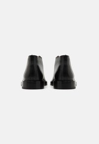 Black leather ankle boots with a smooth texture, rounded toe, and a low block heel. Features a seam detail along the back.