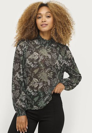 Transparante zwarte blouse met een groen bloemmotief. Heeft een hoge elastische halslijn en lange mouwen met gerimpelde manchetten. Geschreven bij zwarte onderkleding.