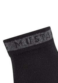 Schwarze Socke mit geripptem Bündchen und hellgrauem Text. Der Stoff hat eine glatte Textur und eine enganliegende Form.
