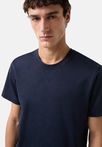 Mørkeblå bomulds T-shirt med rund hals, korte ærmer og V-syning ved halsen, glat tekstur, tætsiddende design.