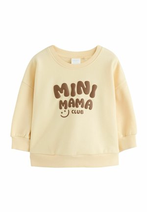 Bluza dla malucha w kolorze kremowym z prążkowanymi mankietami i dołem, z brązowym tekstem "MINI MAMA CLUB" i małą uśmiechniętą buźką.