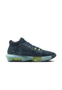 Chaussure de sport bleu foncé avec tissu texturé, semelle mouchetée vert menthe, accents jaune néon et motif floral sur la zone du talon.