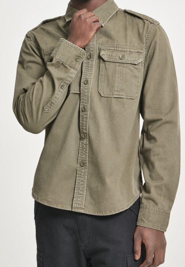 Olivgrön långärmad skjorta i bomull, med knäppning framtill, två bröstfickor och axelklaffar. Slät textur, rundad nederkant.