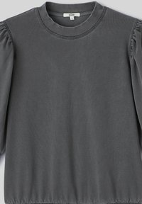 Top gris à manches longues en tissu doux. Il présente un décolleté rond, des coutures d'épaule froncées et un ourlet ajusté.