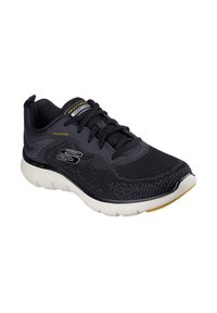 Zapato deportivo negro con parte superior de malla, diseño con cordones, suela blanca, acento amarillo y superficie texturizada para transpirabilidad y apoyo.