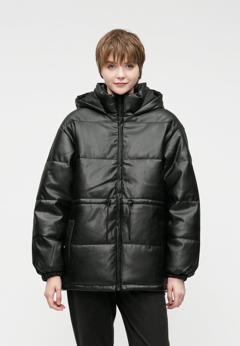 Czarna pikowana kurtka z błyszczącym wykończeniem, z kapturem, zamkiem z przodu, regulowanym sznurkiem oraz elastycznymi mankietami. Posiada obszerne kieszenie boczne.