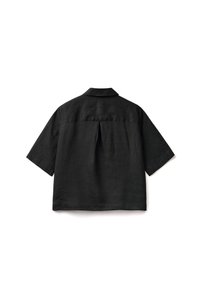 Camicetta nera a maniche corte in lino con colletto, caratterizzata da una piega sul retro e una vestibilità rilassata. Il tessuto ha una texture sottile.