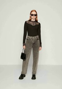 Black ribbed long-sleeve top with lace collar, gray high-waisted jeans, black chunky shoes, and a small black handbag.