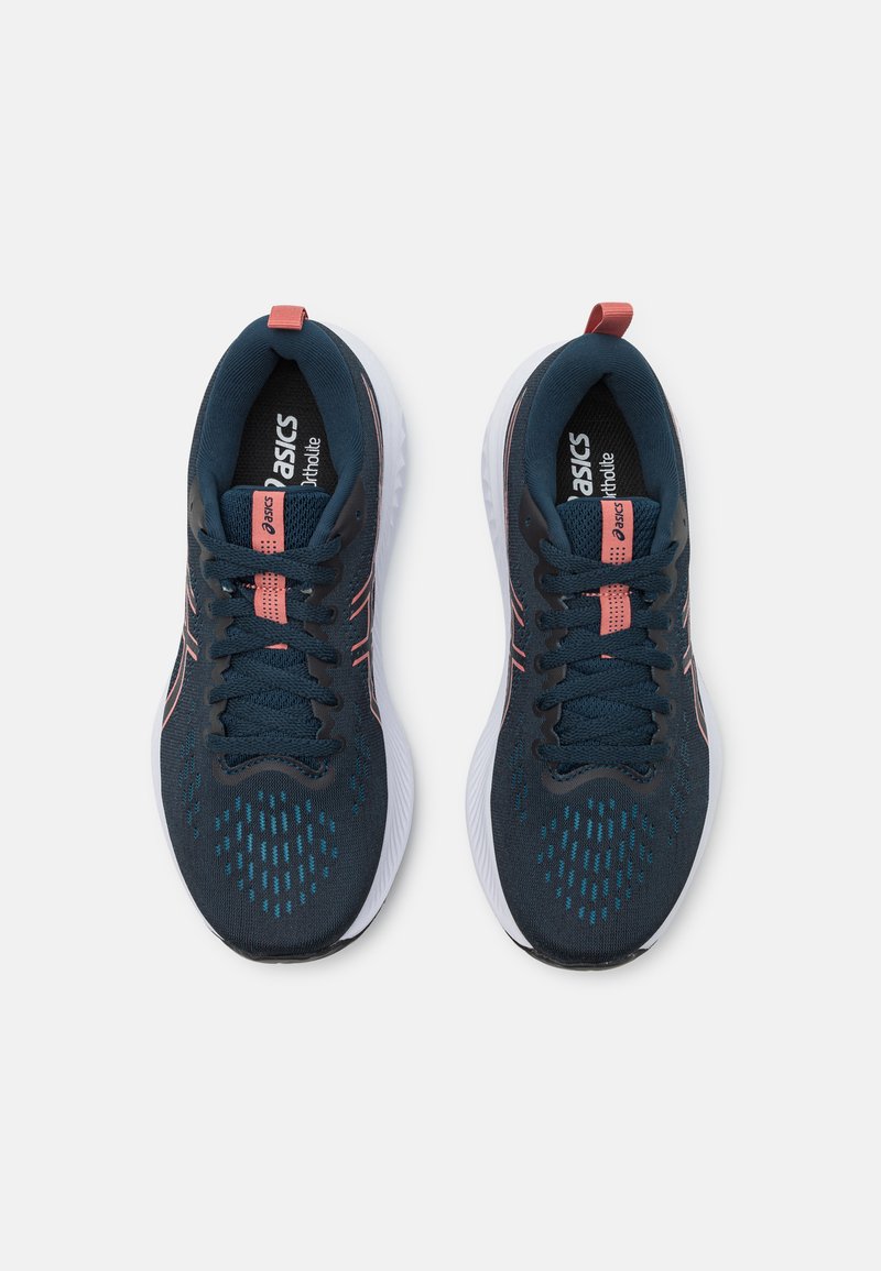 Baskets de sport bleu foncé avec une tige en mesh respirant, des accents roses et une semelle texturée pour une meilleure adhérence. Présente des lacets tissés et un logo.