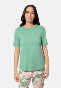 Mintgroene T-shirt met korte mouwen en een ronde halslijn, gemaakt van een zachte stof, gecombineerd met bloemenpatroonbroek in roze en groene tinten.