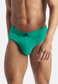 Caleçons verts en tissu extensible avec une couleur unie et une taille élastique présentant des accents de logo noirs. Design avant en forme de contour.