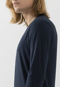 Granatowa koszula z długim rękawem i okrągłym dekoltem, wykonana z miękkiej tkaniny. Posiada dopasowany krój i gładką fakturę, idealna do warstwowania.