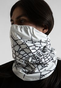 Bufanda de cuello blanca hecha de tela suave, con un patrón geométrico negro con puntos. La abertura elástica permite un fácil uso.