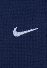 Tessuto a maglia di colore blu navy con un grande logo swoosh Nike bianco. La trama è liscia con un motivo di lavorazione regolare.