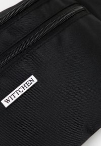 Borsa nera in nylon con due tasche con zip, dotata di un'etichetta rettangolare con il logo WITTCHEN in argento. Superficie testurizzata con cuciture resistenti.