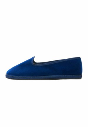 Zapatilla de ante azul con una superficie suave, punta redondeada y un diseño de corte bajo. Presenta una suela de goma flexible y costuras decorativas a lo largo del borde.